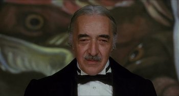 Movie still from “Caravaggio” (1986), directed by Derek Jarman – An older man in a tuxedo with a bow tie; Close Up shot, Low angle