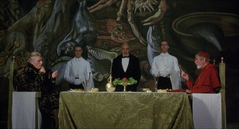 Movie still from “Caravaggio” (1986), directed by Derek Jarman – A group of men standing around a table with food on it; Wide shot, Low angle