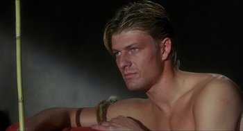 Movie still from “Caravaggio” (1986), directed by Derek Jarman – A man with long blonde hair is holding a banana; Close Up shot, Over the shoulder angle