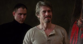 Movie still from “Caravaggio” (1986), directed by Derek Jarman – A man with long hair and a beard standing next to another man with long hair; Close Up shot, Over the shoulder angle