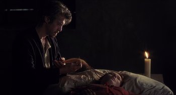 Movie still from “Caravaggio” (1986), directed by Derek Jarman – A man and a woman in a dark room; Medium shot, Over the shoulder angle