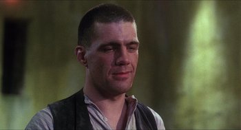 Movie still from “Caravaggio” (1986), directed by Derek Jarman – A person wearing a vest with trees in the background; Close Up shot, Low angle