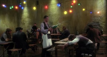 Movie still from “Caravaggio” (1986), directed by Derek Jarman – A man holding a bottle of wine in his hand; Wide shot, High angle