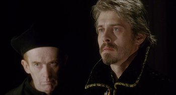 Movie still from “Caravaggio” (1986), directed by Derek Jarman – A man with a beard and mustache and a man with long hair and a mustache; Close Up shot, Over the shoulder angle