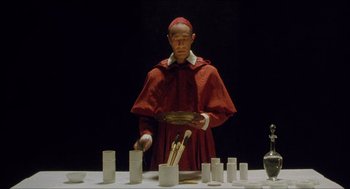 Movie still from “Caravaggio” (1986), directed by Derek Jarman – A man dressed as a cardinal preparing a meal; Medium shot, Low angle