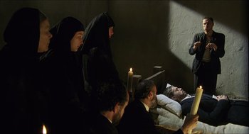 Movie still from “Caravaggio” (1986), directed by Derek Jarman – A group of people sitting in a room with candles; Wide shot, High angle