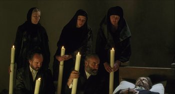 Movie still from “Caravaggio” (1986), directed by Derek Jarman – A group of people holding lit candles next to each other; Wide shot, High angle