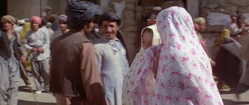 Movie still from “Caravans” (1978), directed by James Fargo – A group of men and women standing next to each other; Medium shot, Over the shoulder angle