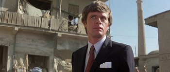 Movie still from “Caravans” (1978), directed by James Fargo – A man in a suit and tie; Close Up shot, Low angle