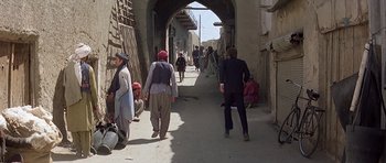 Movie still from “Caravans” (1978), directed by James Fargo – A group of people walking down a narrow street; Wide shot, Over the shoulder angle