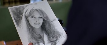 Movie still from “Caravans” (1978), directed by James Fargo – A person holding up a picture of a woman with long hair; Extreme Close Up shot, Over the shoulder angle