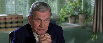 Movie still from “Caravans” (1978), directed by James Fargo – An older man in a black suit and white tie; Close Up shot, Over the shoulder angle