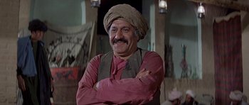 Movie still from “Caravans” (1978), directed by James Fargo – An old man with a turban is posing for a picture; Medium shot, Low angle