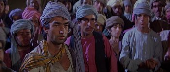 Movie still from “Caravans” (1978), directed by James Fargo – A group of people in a crowd wearing turbans; Medium shot, Low angle