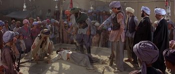 Movie still from “Caravans” (1978), directed by James Fargo – A group of people standing around a dead body; Wide shot, High angle