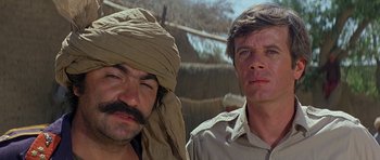 Movie still from “Caravans” (1978), directed by James Fargo – Two men standing next to each other in the desert; Close Up shot, Low angle