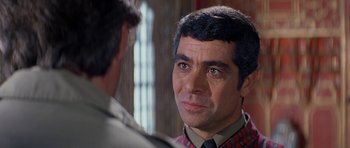 Movie still from “Caravans” (1978), directed by James Fargo – A person wearing a suit and tie; Close Up shot, Over the shoulder angle