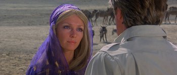 Movie still from “Caravans” (1978), directed by James Fargo – A woman in a purple veil standing next to a man in a field; Close Up shot, Over the shoulder angle