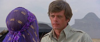 Movie still from “Caravans” (1978), directed by James Fargo – A person wearing a jacket; Close Up shot, Over the shoulder angle