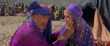 Movie still from “Caravans” (1978), directed by James Fargo – A man and a woman dressed in purple; Medium shot, Over the shoulder angle