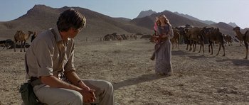 Movie still from “Caravans” (1978), directed by James Fargo – A man and a woman in a field with horses; Wide shot, Over the shoulder angle