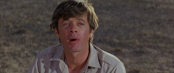 Movie still from “Caravans” (1978), directed by James Fargo – A person wearing a white shirt; Close Up shot, Low angle