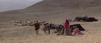 Movie still from “Caravans” (1978), directed by James Fargo – A group of people standing in the middle of the desert; Extreme Wide shot, High angle