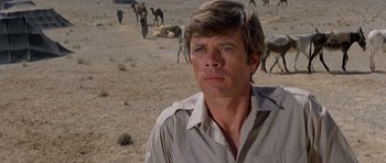 Movie still from “Caravans” (1978), directed by James Fargo – A person in a field with animals; Close Up shot, Low angle