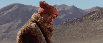 Movie still from “Caravans” (1978), directed by James Fargo – An older man with a red turban and a beard; Close Up shot, Low angle
