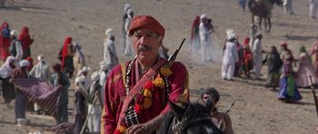 Movie still from “Caravans” (1978), directed by James Fargo – An old man in a red shirt is on a horse; Medium shot, Over the shoulder angle