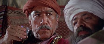 Movie still from “Caravans” (1978), directed by James Fargo – An older man wearing a red turban and a mustache; Close Up shot, Low angle