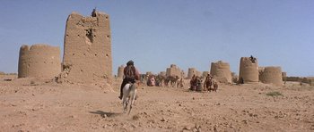 Movie still from “Caravans” (1978), directed by James Fargo – A group of people riding horses in the desert; Extreme Wide shot, Low angle