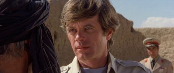 Movie still from “Caravans” (1978), directed by James Fargo – A person wearing a shirt; Close Up shot, Over the shoulder angle