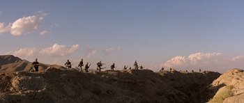Movie still from “Caravans” (1978), directed by James Fargo – A group of people sitting on top of a hill; Extreme Wide shot, Low angle