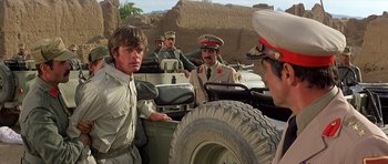 Movie still from “Caravans” (1978), directed by James Fargo – A group of men in military uniforms in an open jeep; Medium shot, Over the shoulder angle