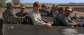 Movie still from “Caravans” (1978), directed by James Fargo – A group of men sitting on top of a boat; Medium shot, Low angle