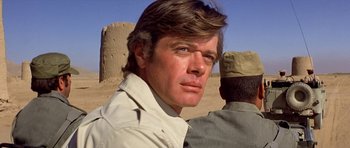 Movie still from “Caravans” (1978), directed by James Fargo – A person wearing a shirt; Close Up shot, Over the shoulder angle