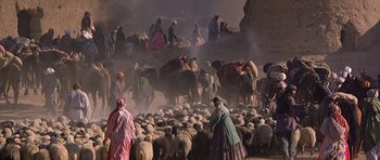Movie still from “Caravans” (1978), directed by James Fargo – A group of people herding a herd of sheep down a road; Extreme Wide shot, High angle