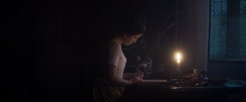 Movie still from “Carmilla” (2019), directed by Emily Harris – A woman writing on a piece of paper in a dark room; Medium shot, Low angle