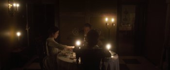 Movie still from “Carmilla” (2019), directed by Emily Harris – A group of people sitting around a table with candles; Medium shot, High angle