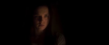 Movie still from “Carmilla” (2019), directed by Emily Harris – A woman is looking at the camera in the dark; Close Up shot, Low angle