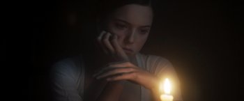 Movie still from “Carmilla” (2019), directed by Emily Harris – A woman sitting in front of a candle in the dark; Close Up shot, Over the shoulder angle