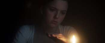 Movie still from “Carmilla” (2019), directed by Emily Harris – A woman is holding a candle in her hand; Close Up shot, Over the shoulder angle
