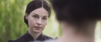 Movie still from “Carmilla” (2019), directed by Emily Harris – A woman is looking into a mirror while wearing a black shirt; Close Up shot, Over the shoulder angle