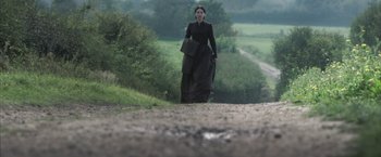 Movie still from “Carmilla” (2019), directed by Emily Harris – A woman walking down a dirt road in a black dress; Wide shot, Low angle