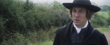 Movie still from “Carmilla” (2019), directed by Emily Harris – A man wearing a black hat and a black coat; Close Up shot, Over the shoulder angle