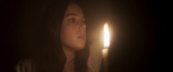 Movie still from “Carmilla” (2019), directed by Emily Harris – A woman looking at a lit candle in the dark; Close Up shot, Low angle