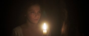 Movie still from “Carmilla” (2019), directed by Emily Harris – A woman is holding a lit candle in the dark; Close Up shot, Over the shoulder angle