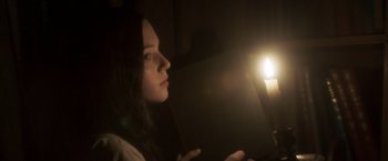 Movie still from “Carmilla” (2019), directed by Emily Harris – A woman sitting in front of a light in a dark room; Close Up shot, Low angle