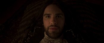 Movie still from “Carmilla” (2019), directed by Emily Harris – A man with long black hair wearing a white shirt; Close Up shot, Overhead angle